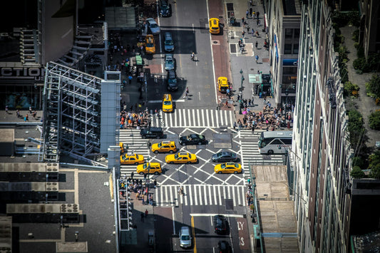 Busy NYC street ariel view with high rise buildings, yellow cabs and crowd