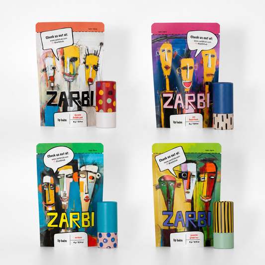 Four ZARBI lip balm packages arranged in a 2x2 grid on a white background, each showing a colorful illustrated pouch and a matching balm tube. The packaging features bold, playful graphics with the brand name ZARBI prominently displayed.