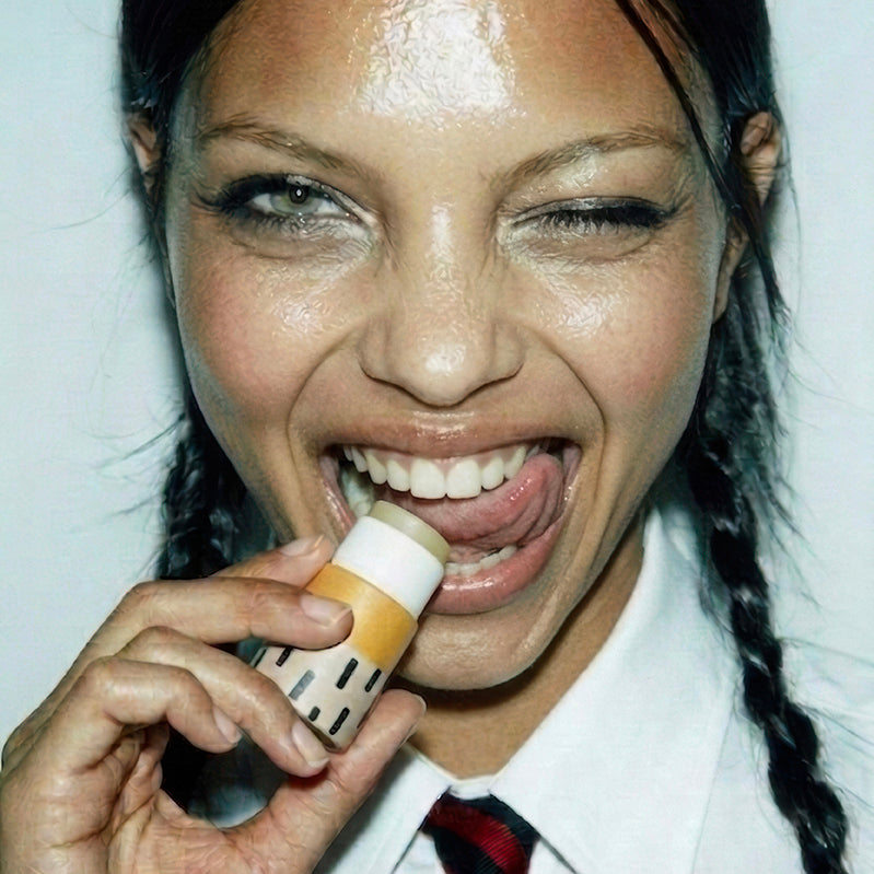 Model holding Zarbi Sea Buckthorn vegan lip balm in yellow patterned paper packaging.